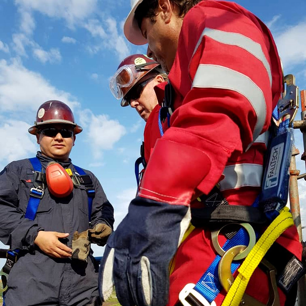 Personnel wearing protective equipment and harnesses during an outdoor activity.