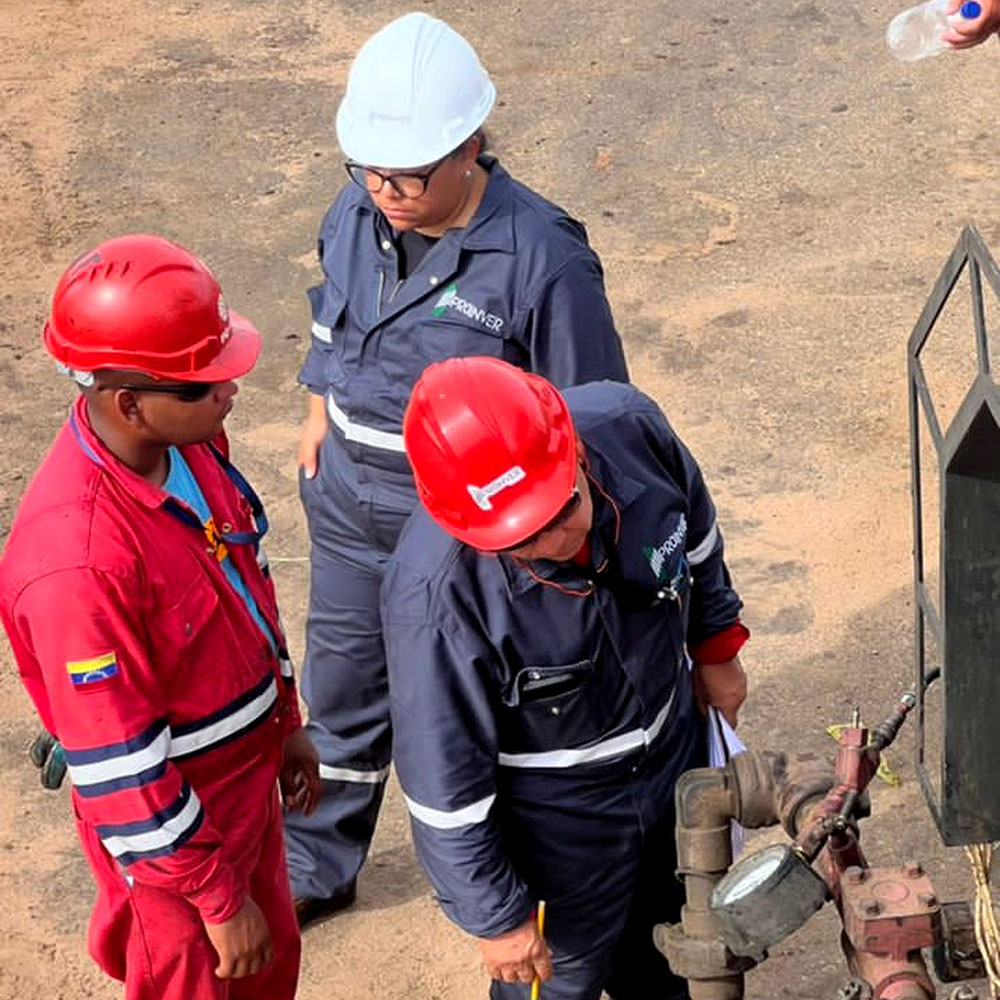 Personnel wearing hard hats examining a connection or equipment in the field.